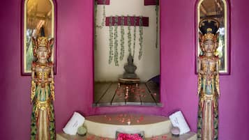 Un santuario con estatuas, un espejo y un pequeño altar adornado con flores y velas.