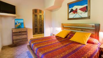 Un dormitorio con una cama, una mesita de noche, un armario de madera y un cuadro en la pared.