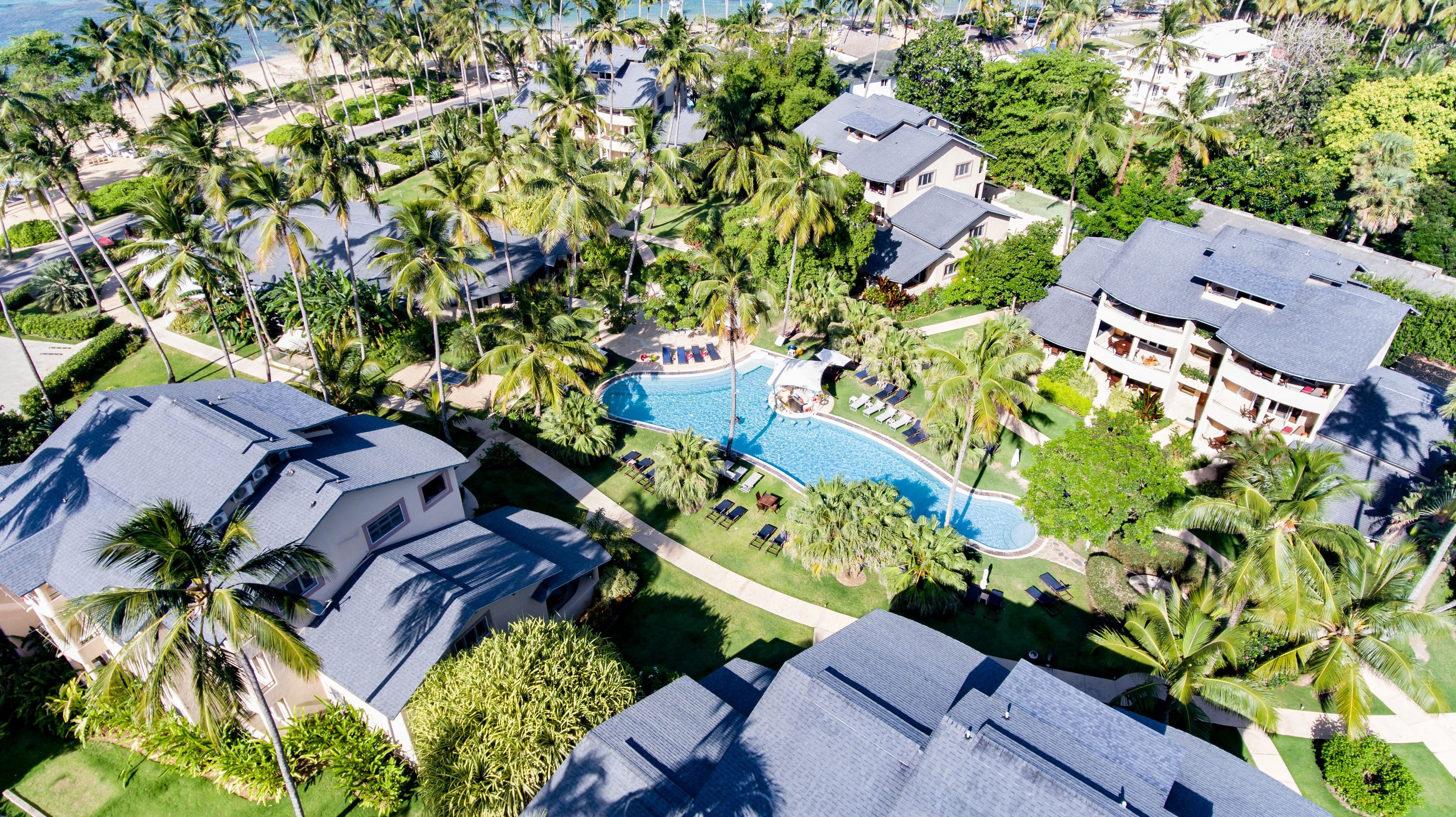An aerial view of a residential area with a swimming pool surrounded by palm trees and houses.