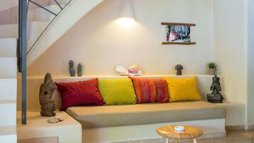 Ein Wohnzimmer mit einer Couch, Kissen, einem kleinen Tisch und einer Treppe.