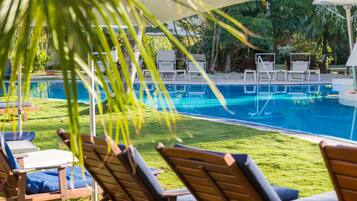 Un área junto a la piscina con sillones de descanso y sombrillas.