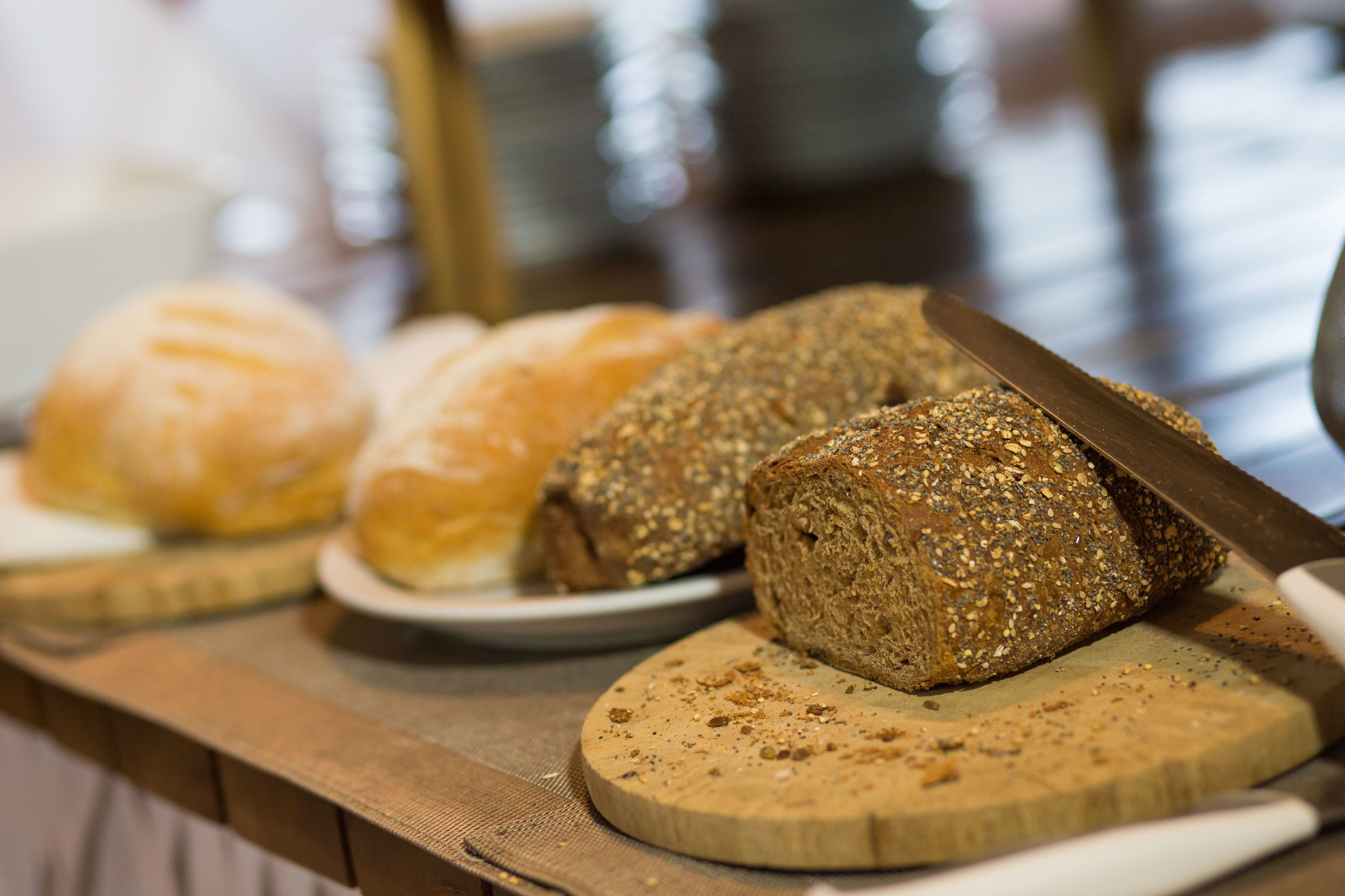 A variety of breads on a wooden board with a knife.