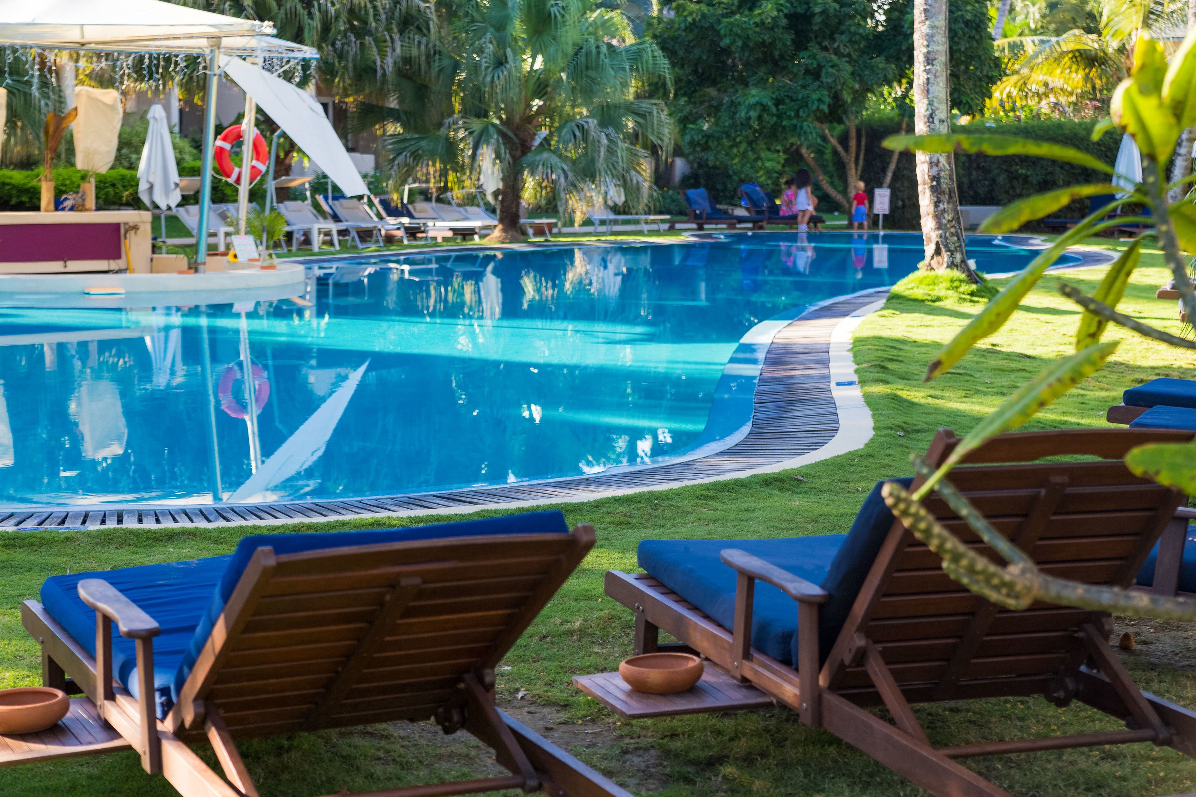 A pool area with lounge chairs and a shaded area.