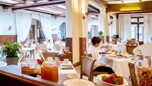 A restaurant with tables set for breakfast, including plates of strawberries and a pitcher of tea.