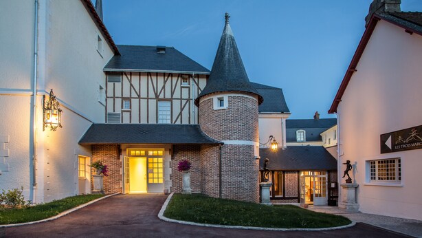 A historic building with a turret, a traditional facade, and a well-lit entrance.