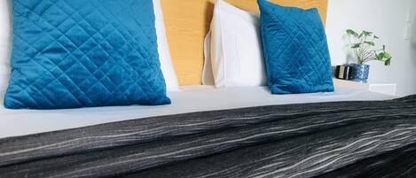 A bed with a wooden headboard, blue and white pillows, and a dark striped bedspread.