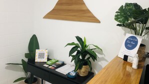 A reception desk with a wooden sign, a welcome sign, a QR code, and a plant. - Blue Haven Motel (Tauranga)