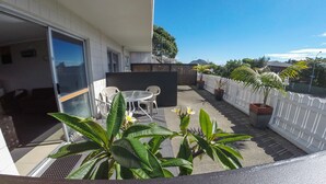 A balcony with a seating area, potted plants, and a white fence. - Blue Haven Motel (Tauranga)