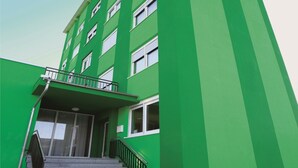 Un edificio de varios pisos con fachada verde y ventanas blancas.