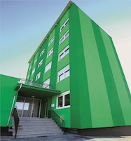 Ein mehrstöckiges Gebäude mit grüner Fassade und weißen Fenstern.