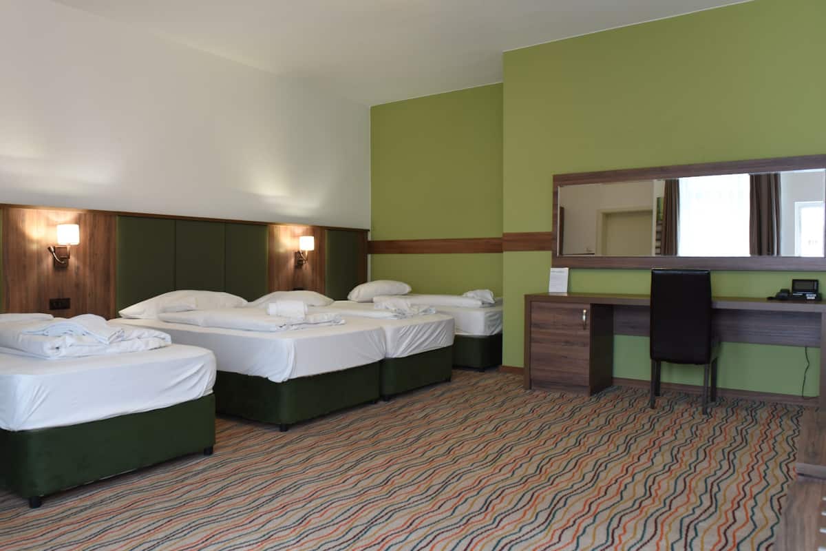 Una habitación de hotel con dos camas, un escritorio, una silla y un espejo grande.