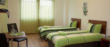 A room with two beds, a small table, and a chair.