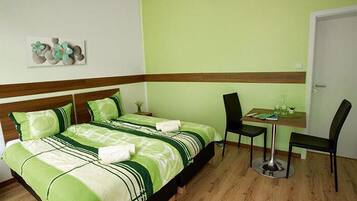 Une chambre d’hôtel bien rangée, avec un lit, une petite table et une chaise.