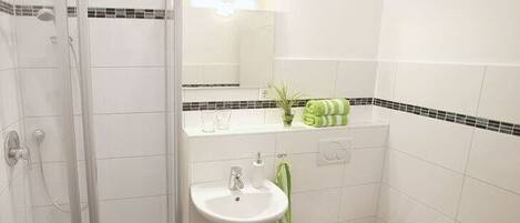 A bathroom with a glass shower enclosure, a sink, a toilet, and a towel rack.