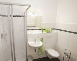 Un baño con cabina de ducha de vidrio, un lavabo, un inodoro y un perchero para toallas.