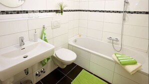 Un baño moderno con lavamanos, inodoro y bañera blancos.