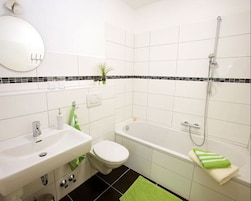 Ein modernes Badezimmer mit Waschbecken, Toilette und Badewanne – alles in Weiß.
