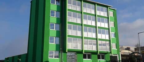 Un edificio verde con varias ventanas y un letrero en la fachada.