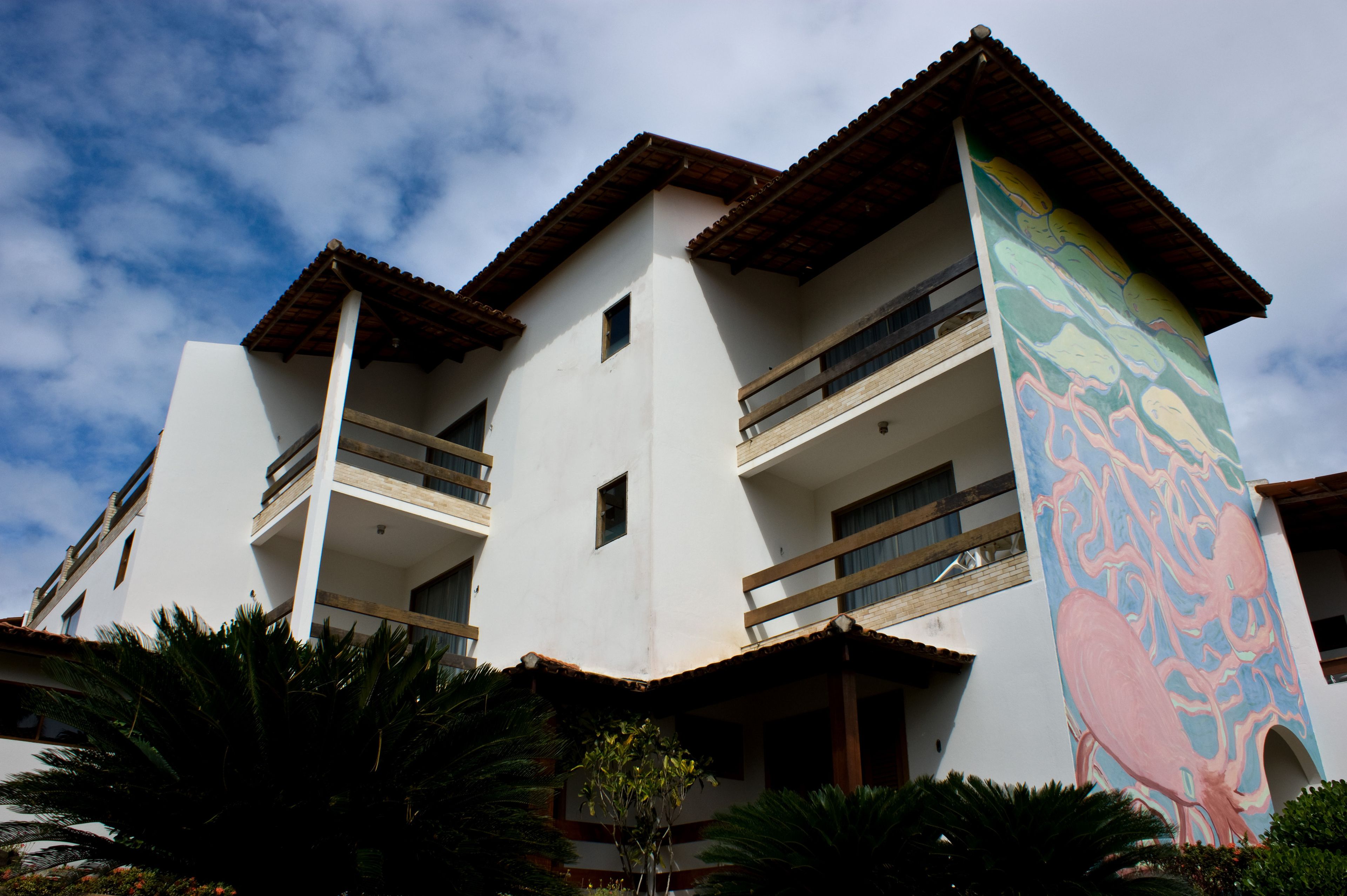 A multi-story building with balconies and a large mural on one side.