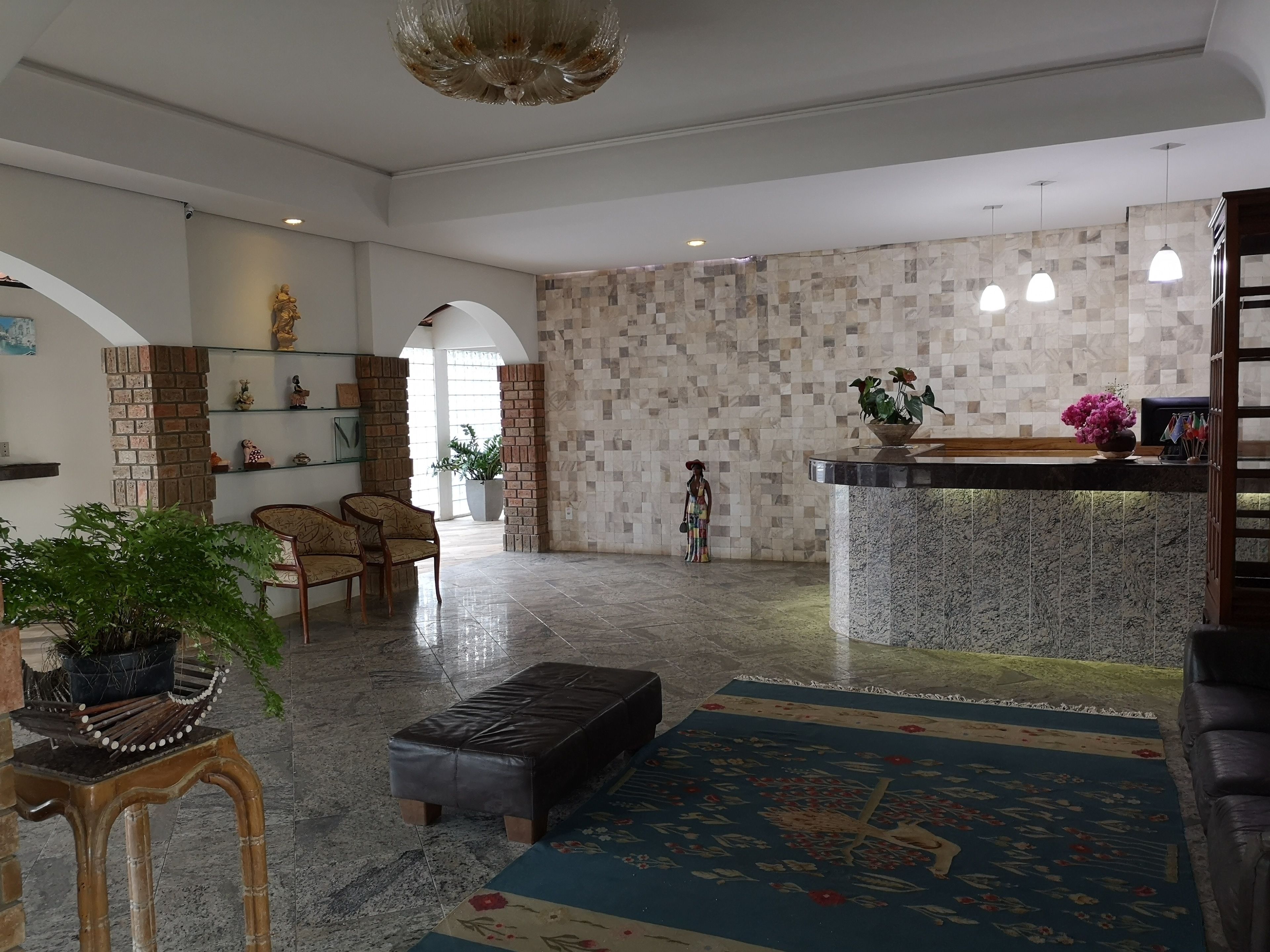 Um hall amplo com balcão de atendimento, área de estar e uma estátua decorativa.