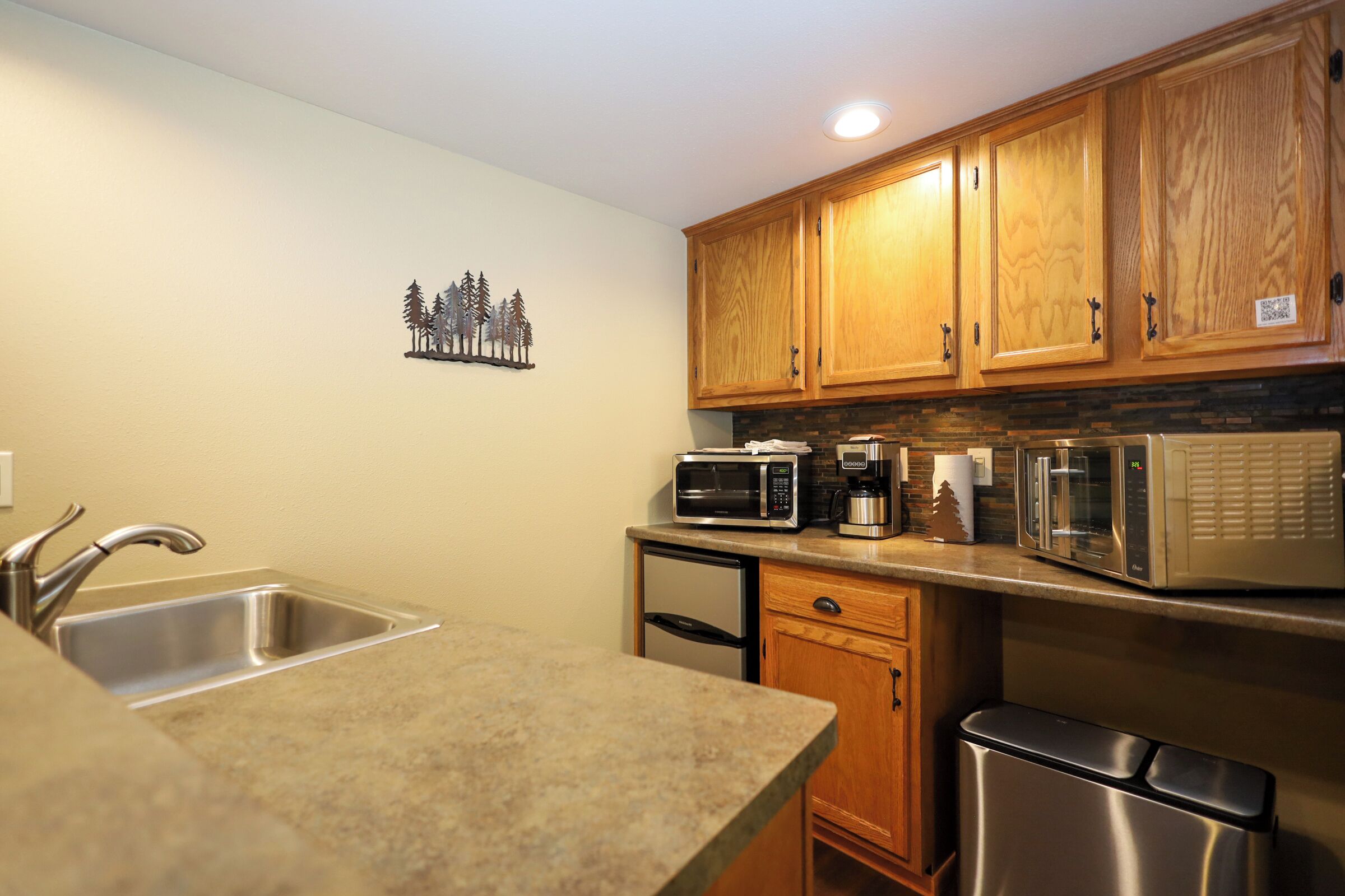 A kitchen with wooden cabinets, a stainless steel sink, and a built-in microwave.