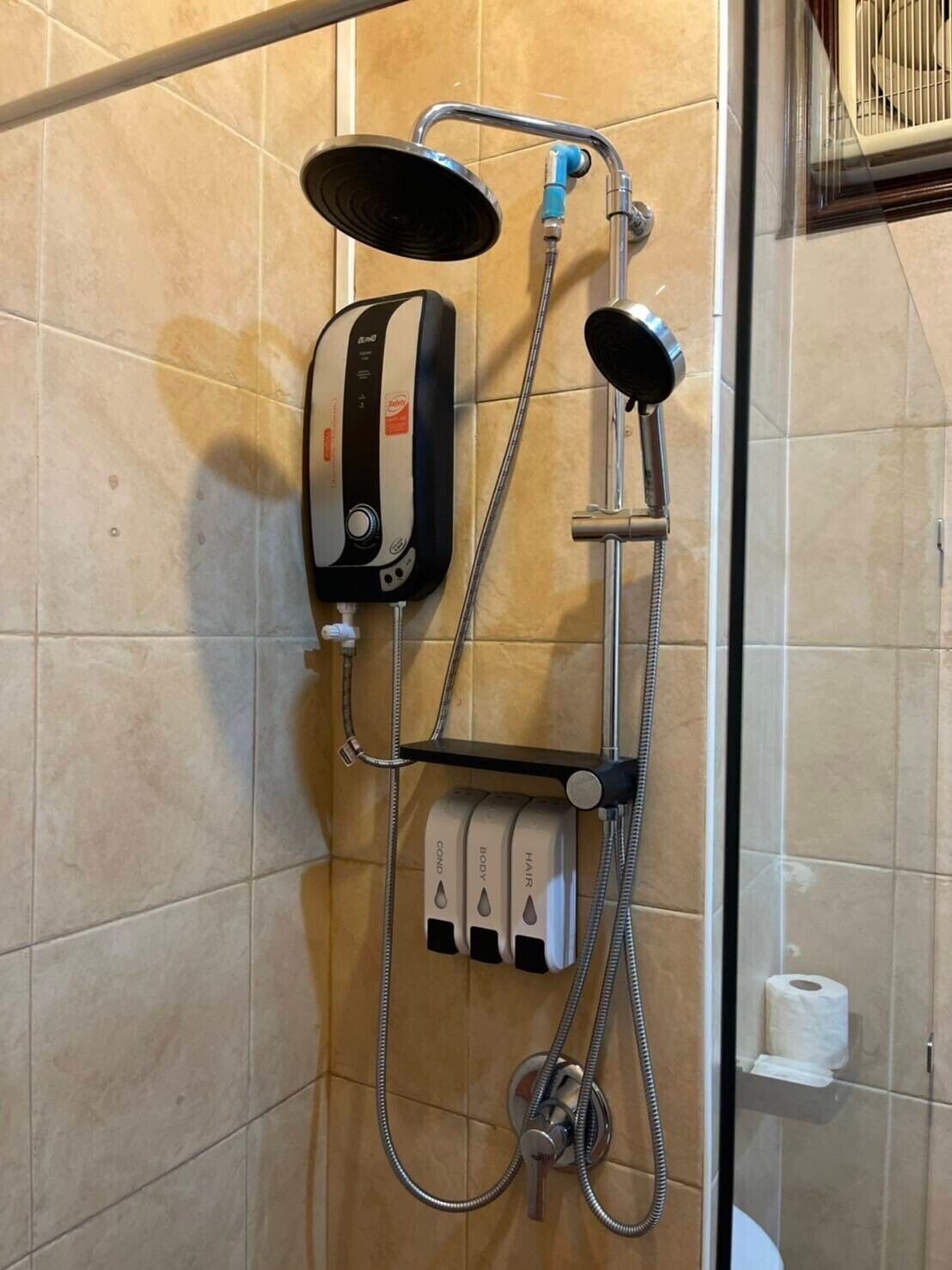 A shower area with a handheld showerhead, a fixed showerhead, and a handheld massager.