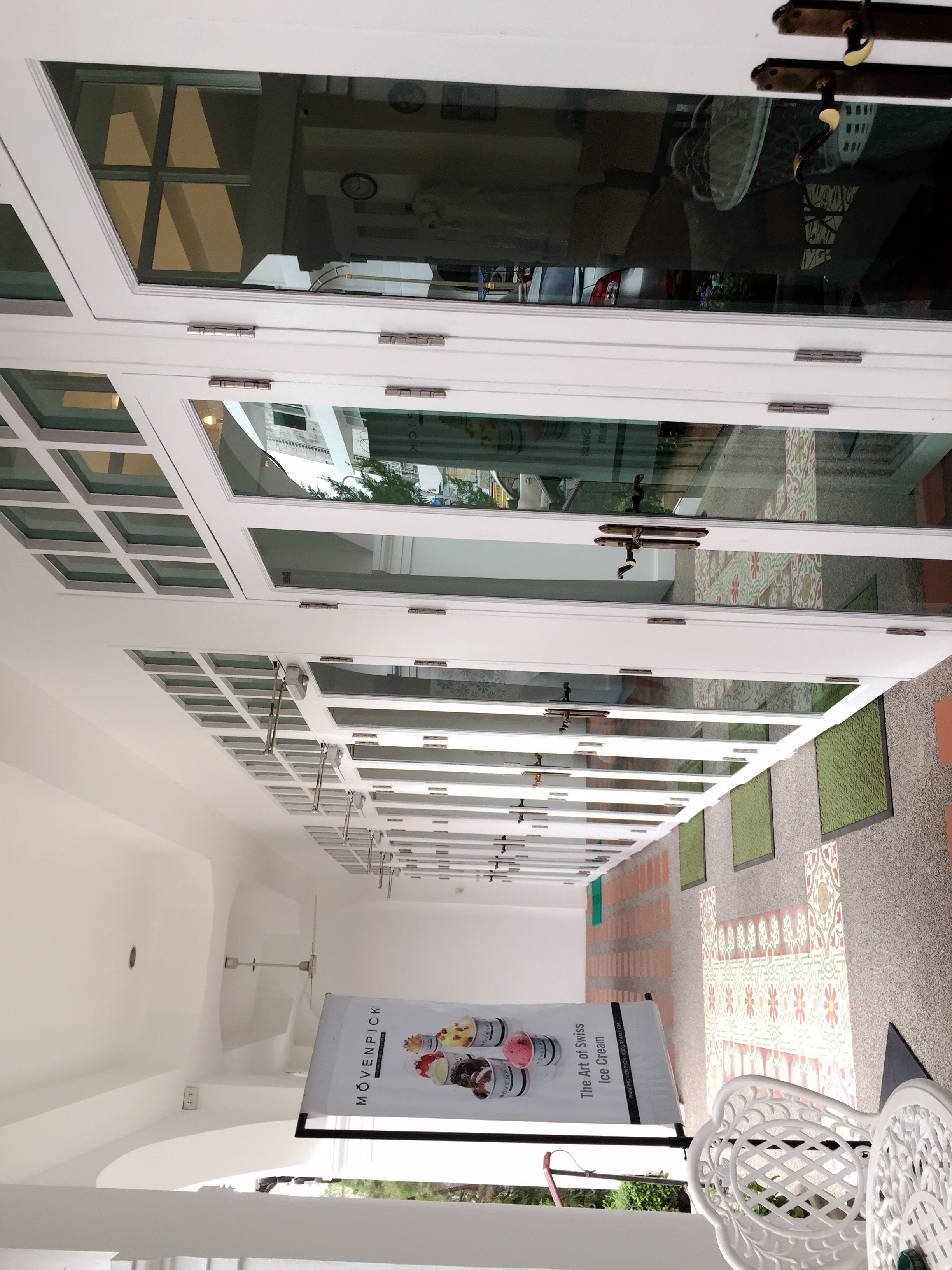 A modern interior with a high ceiling, glass windows, and a poster advertising ice cream.