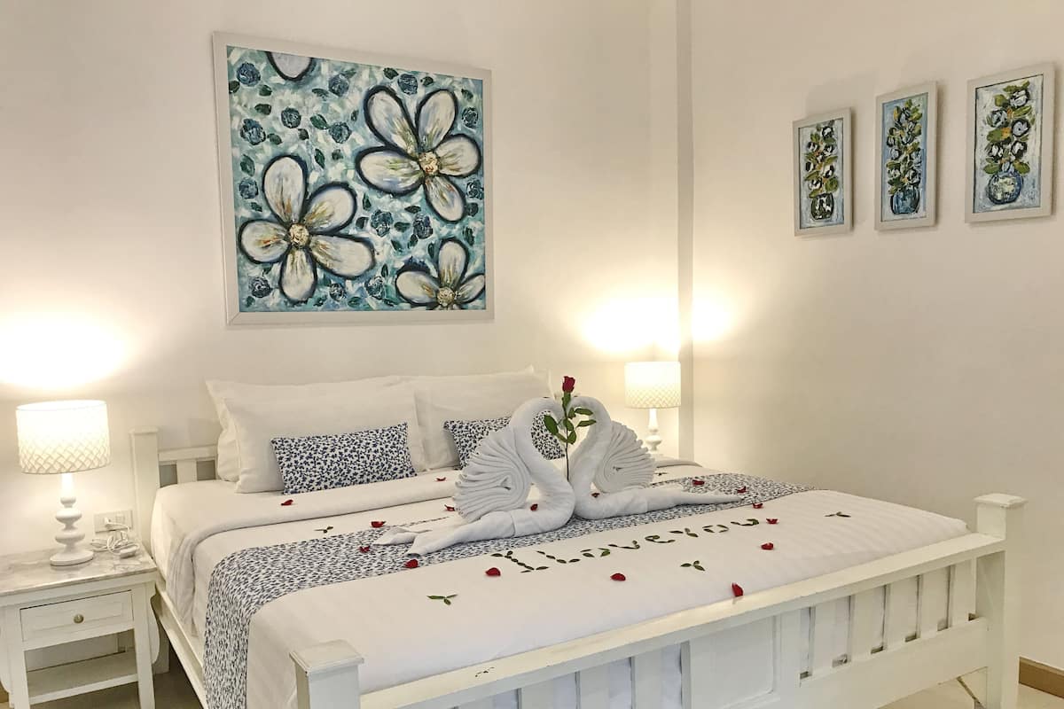 Un dormitorio ordenado con una cama, dos mesitas de noche y decoración en la pared.