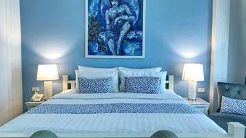 A bedroom with a bed, two bedside lamps, a nightstand, a chair, and a painting on the wall.
