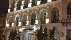 Un edificio de varios pisos con un estilo arquitectónico clásico, que presenta ventanas en arco y balcones.