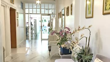 A spacious hallway with marble flooring, a ceiling fan, and a seating area with a sofa and armchairs.