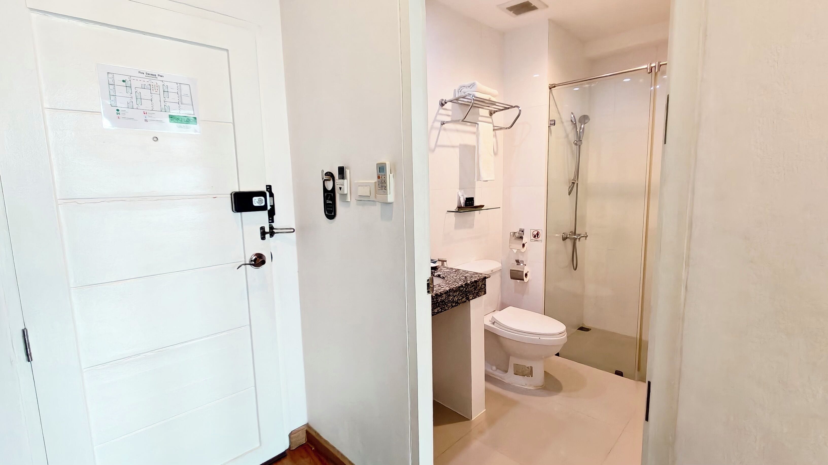 Un baño con inodoro, lavamanos, toallero y ducha.