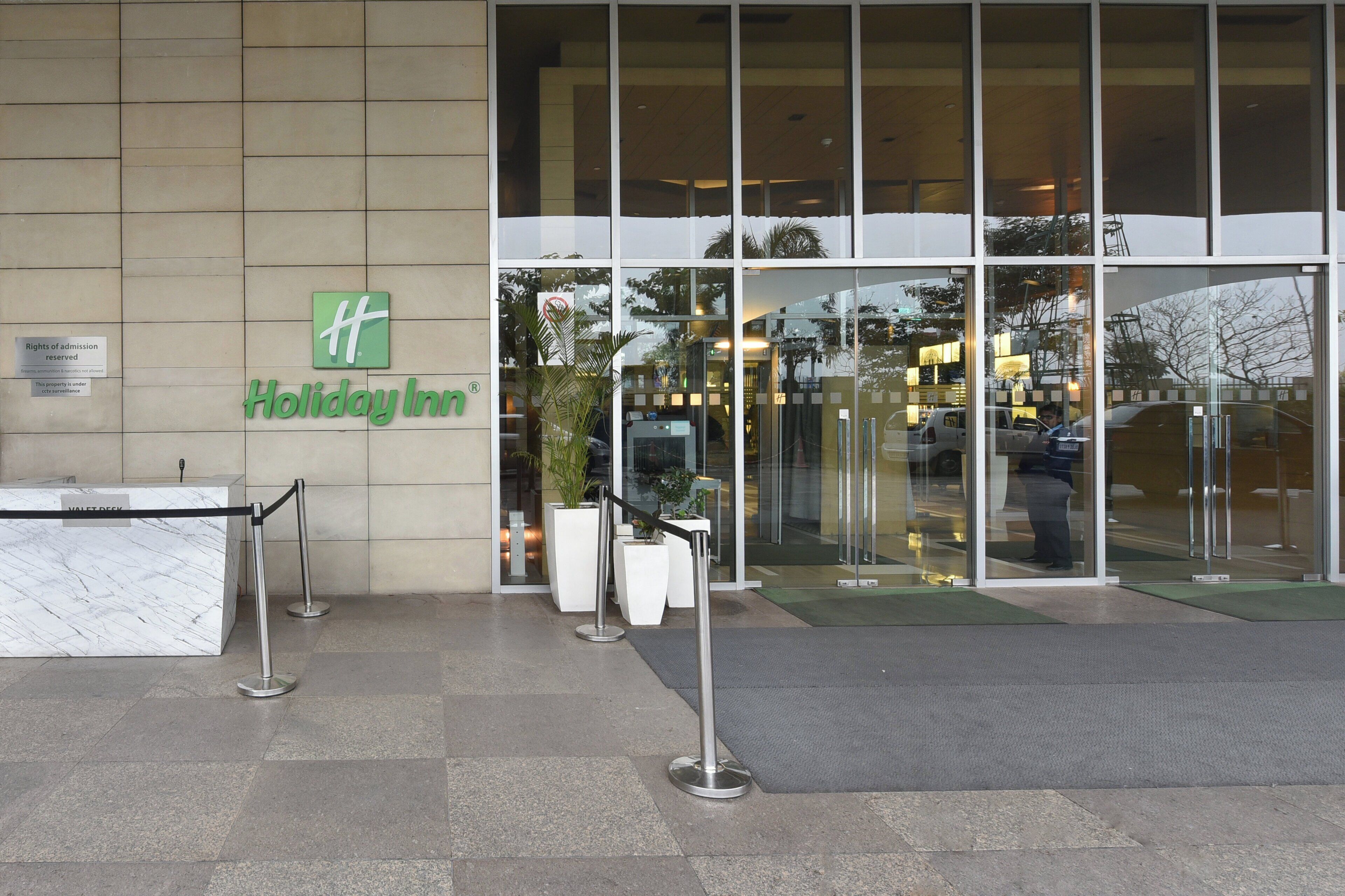 A Holiday Inn entrance with a marble reception desk, a glass door, and a sign indicating rights of admission reserved.