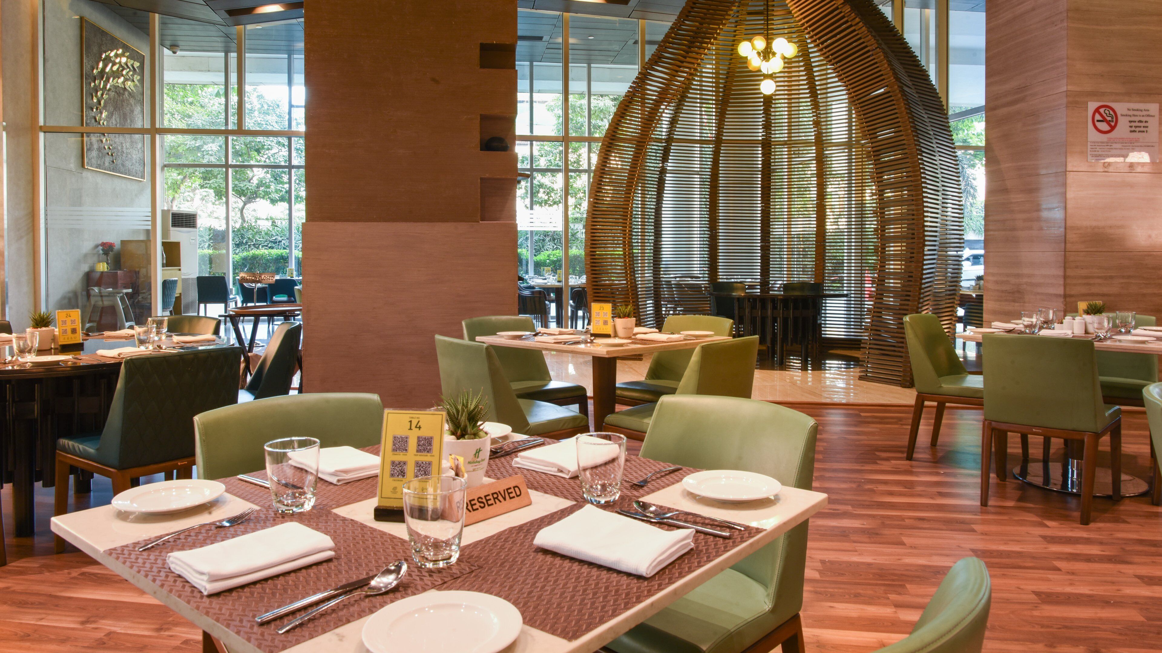 Een restaurant met gedekte tafels, stoelen en een grote houten constructie op de achtergrond.