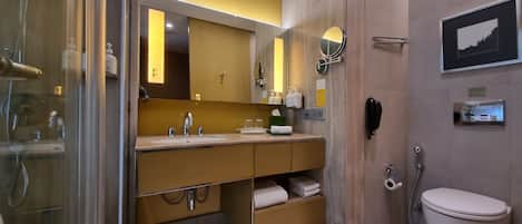 A modern bathroom with a glass shower enclosure, a wooden vanity with a sink, a mirror, and a toilet.