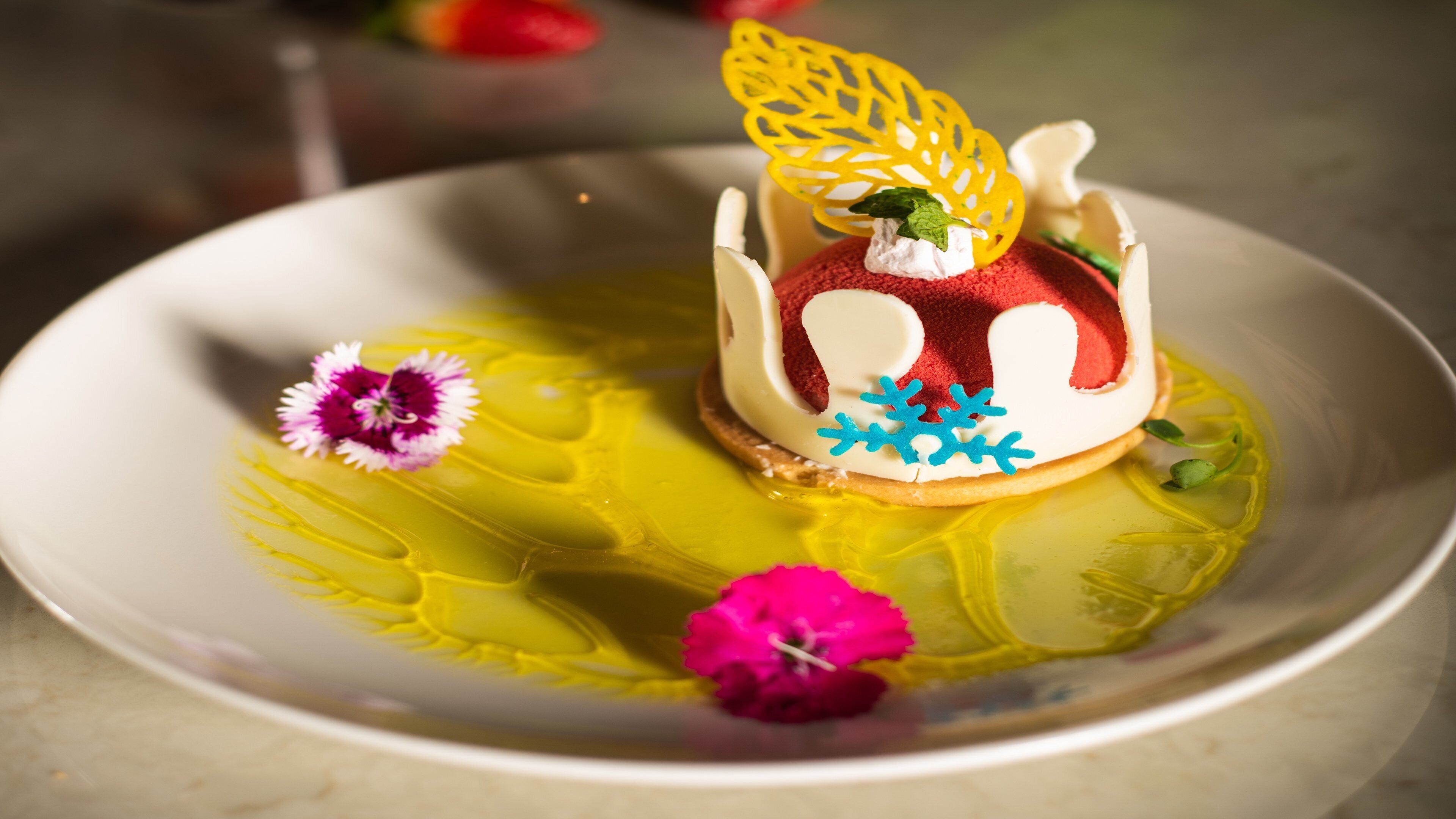 Un postre en un plato con salsa amarilla y detalles decorativos.