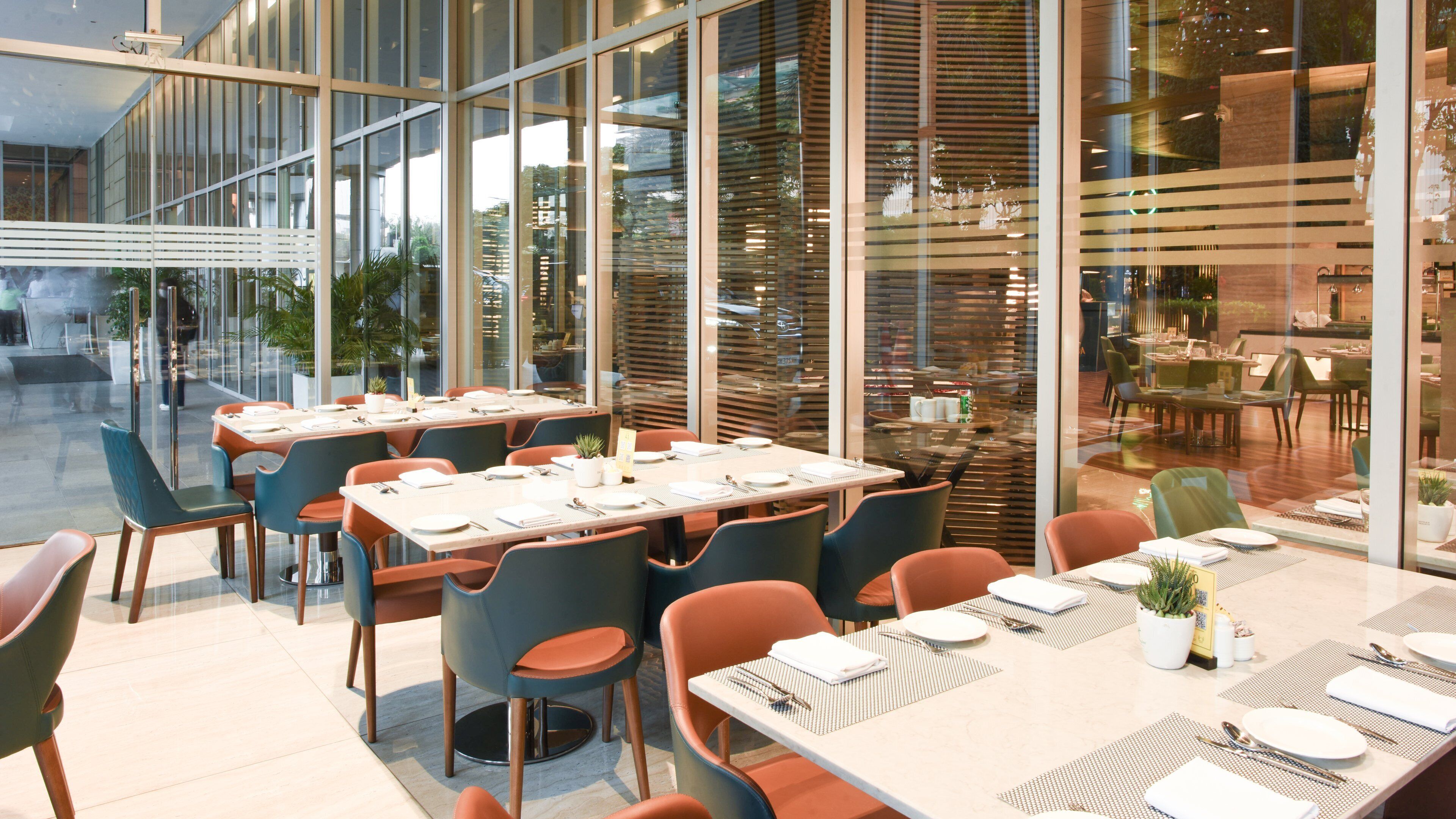 A modern dining area with glass partitions, multiple tables, and chairs.