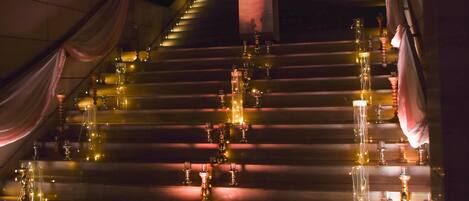 Un escalier à plusieurs niveaux, chacun étant décoré de bougies et de guirlandes lumineuses, créant une atmosphère chaleureuse.