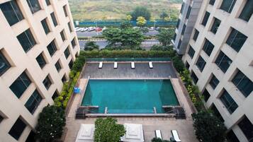 Piscina no terraço com espreguiçadeiras e vista para a paisagem urbana.