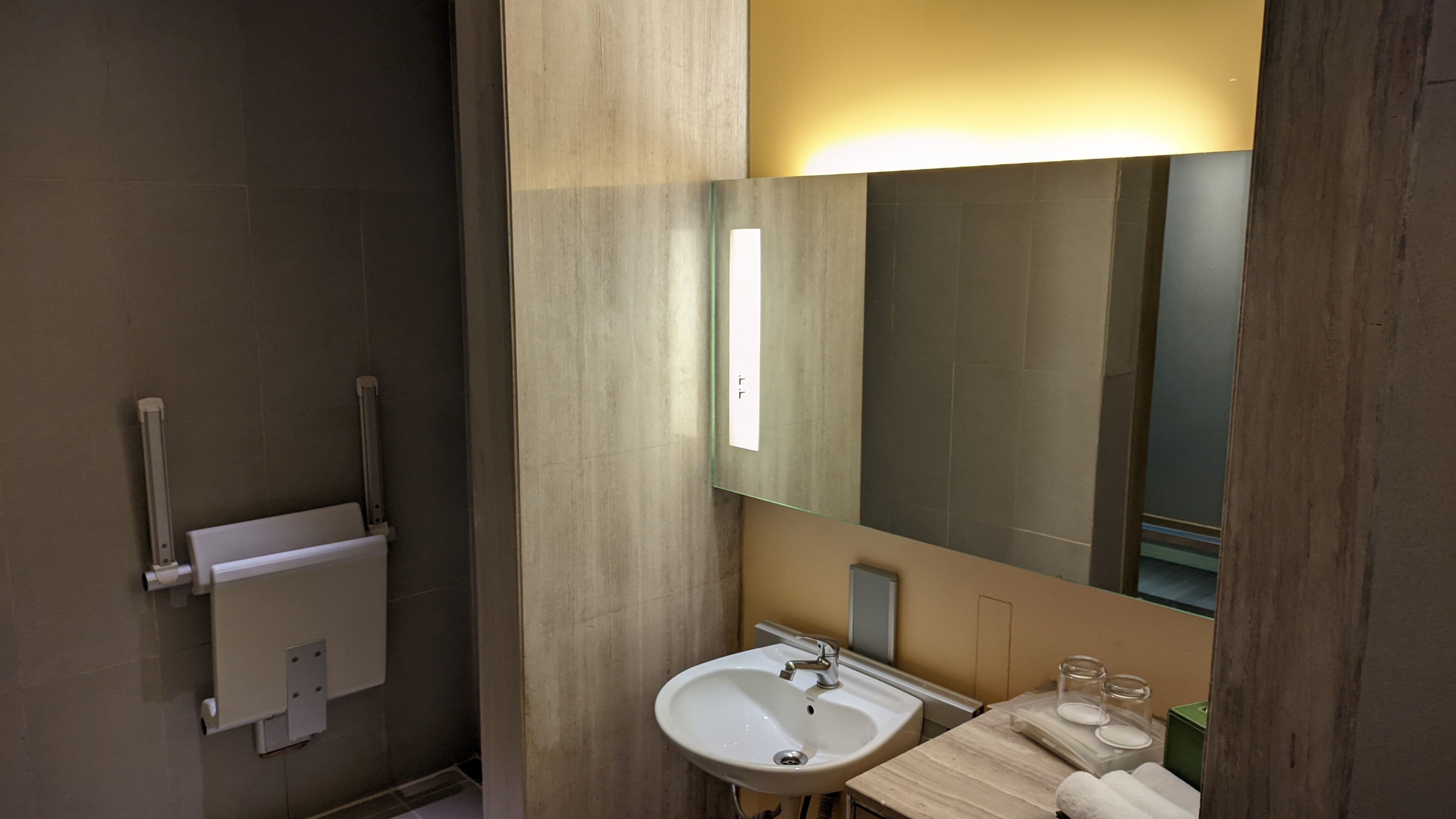 Ein modernes Badezimmer mit Waschbecken, Spiegel und Handtuchhalter.