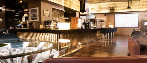 A modern bar area with a curved counter, bar stools, and a glass table.