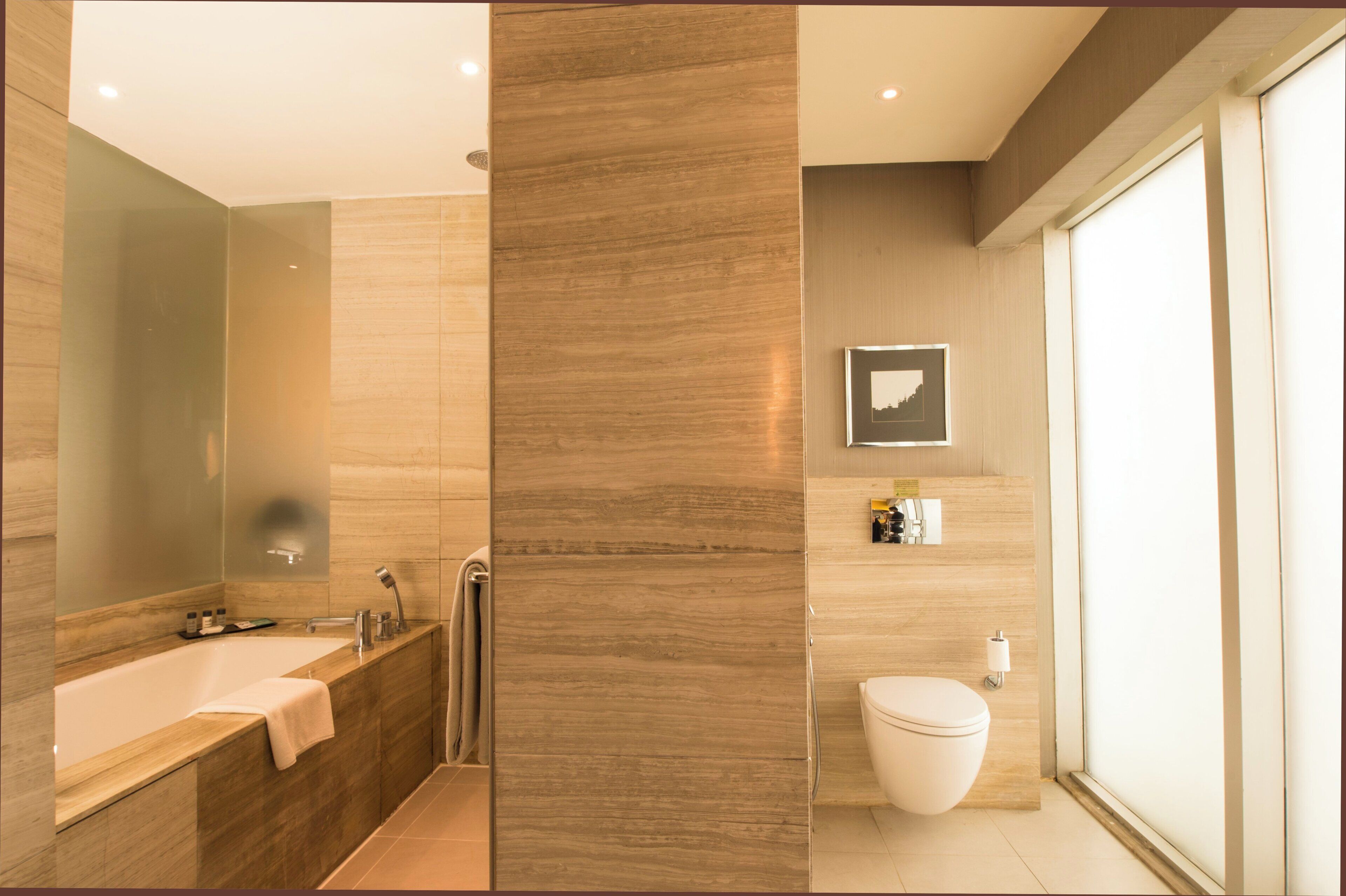 A modern bathroom with a bathtub, toilet, and shower.