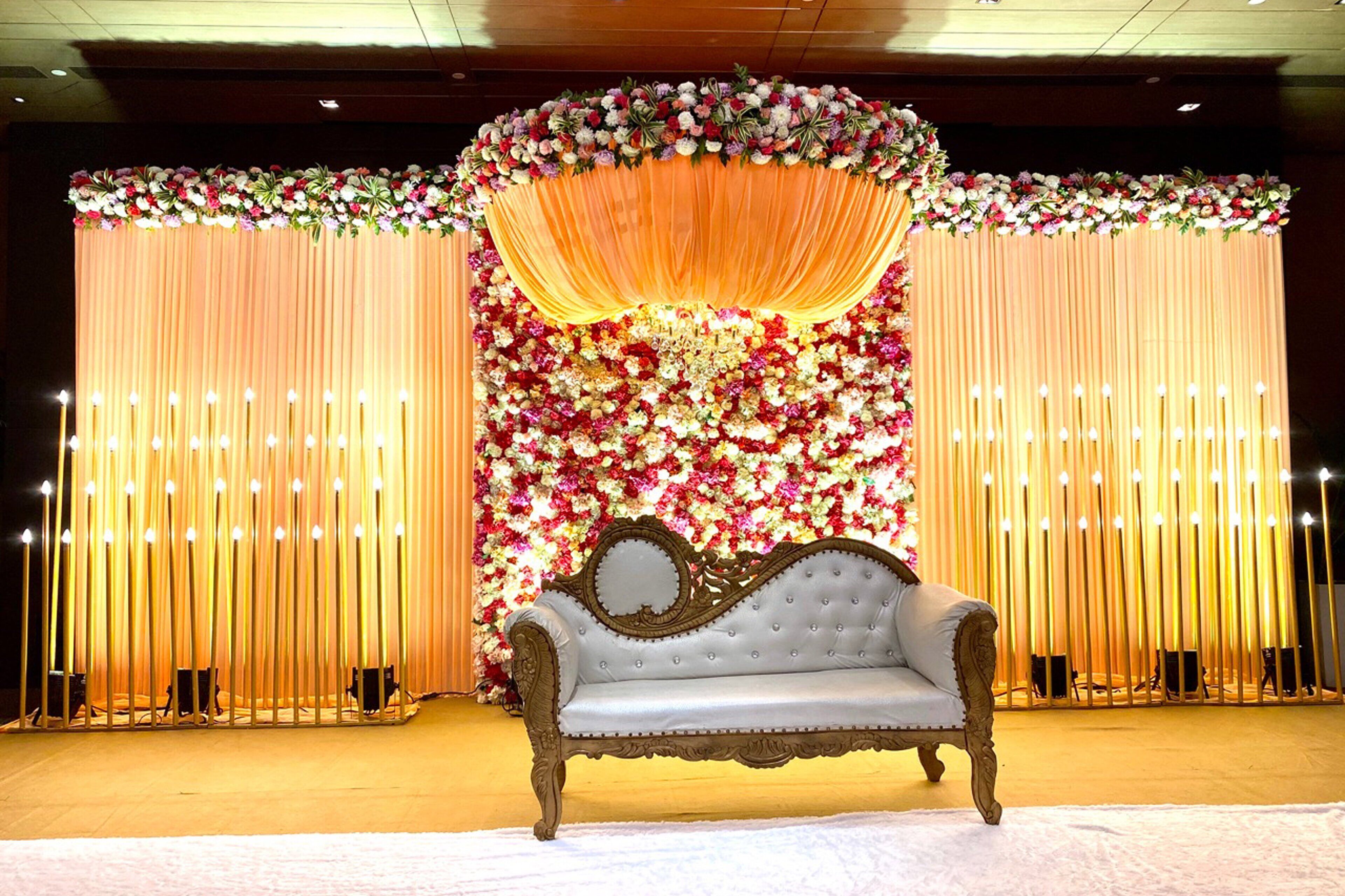 A stage with a floral backdrop, a draped curtain, and a vintage sofa.