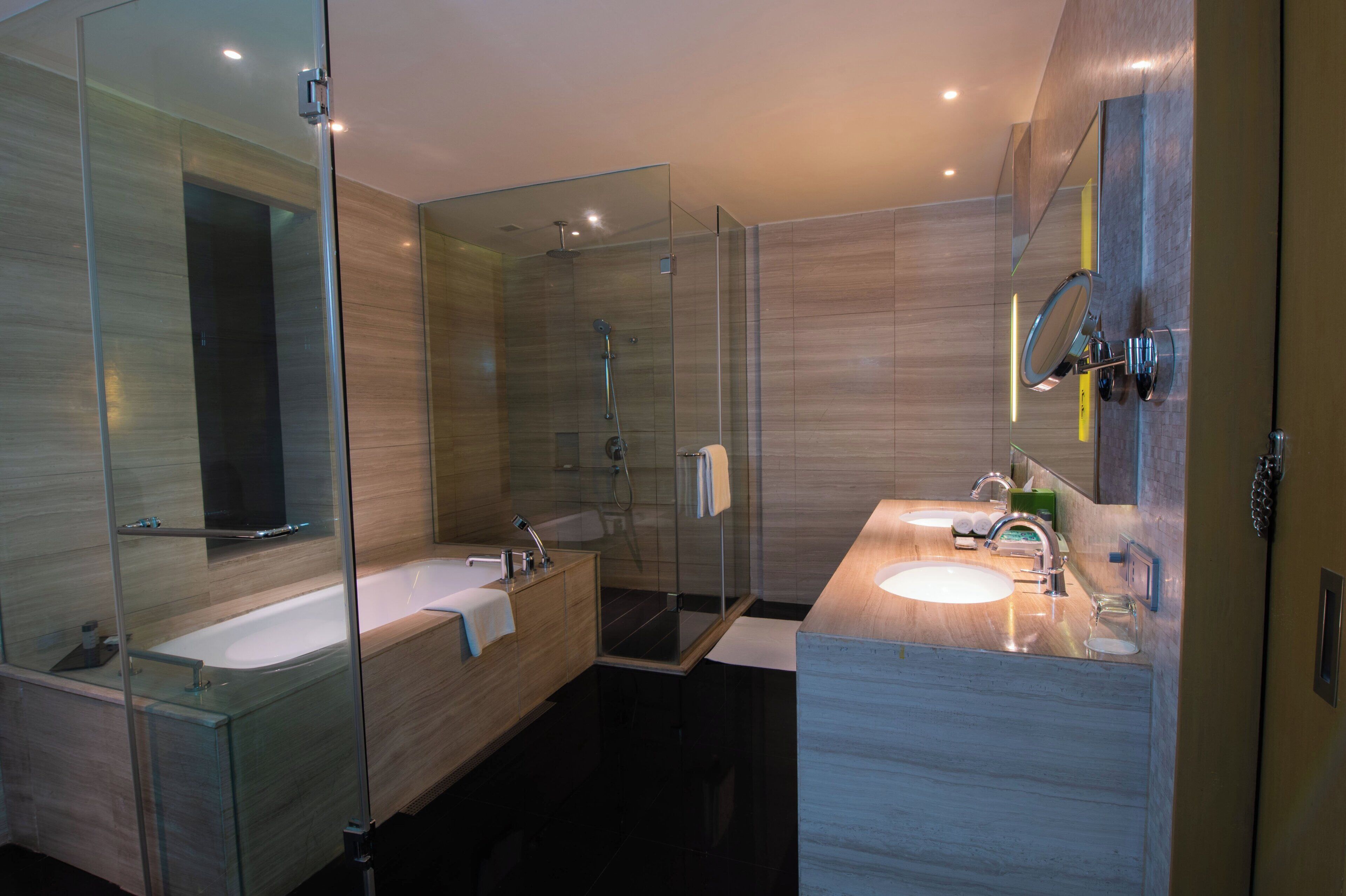 A modern bathroom with a glass-enclosed shower, a freestanding bathtub, and a vanity with a mirror.