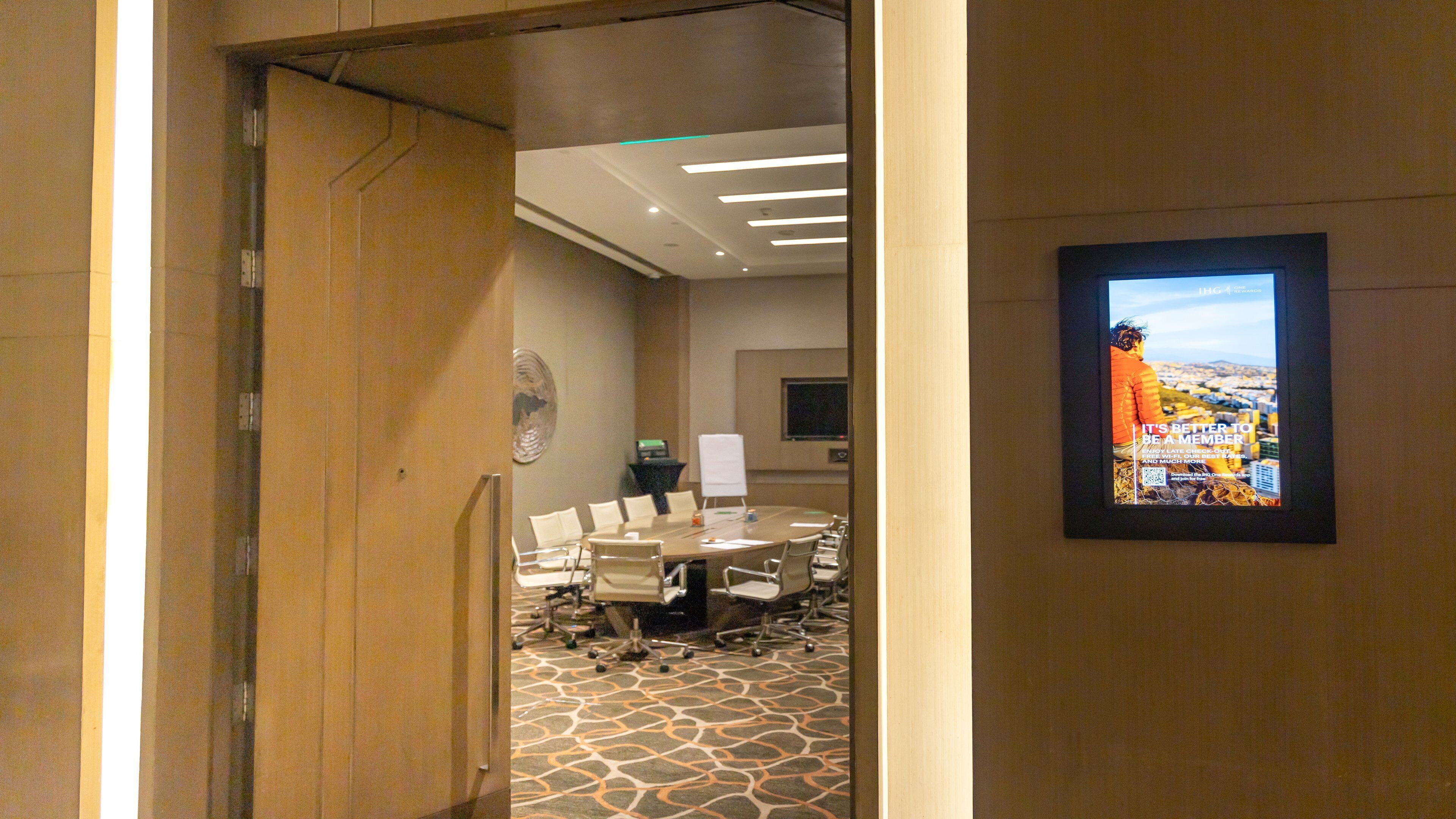 A conference room with a round table, chairs, a whiteboard, and a framed picture on the wall.