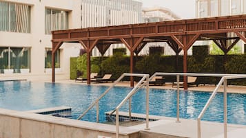 Una piscina con muelle de madera y sillas de descanso.