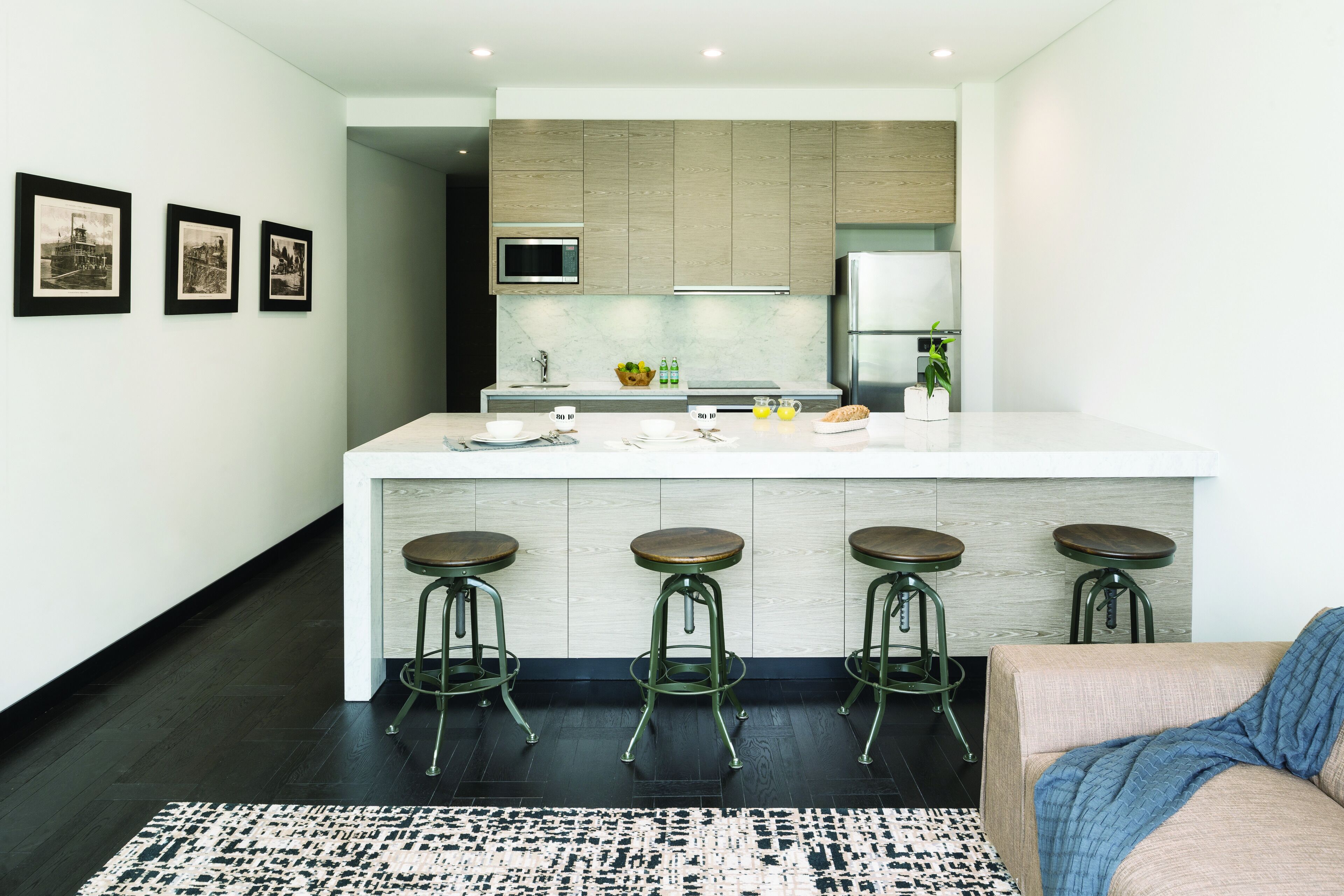 A modern kitchen with a central island, bar stools, and a dining area.