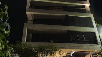A multi-story building with illuminated balconies and a well-lit entrance area.