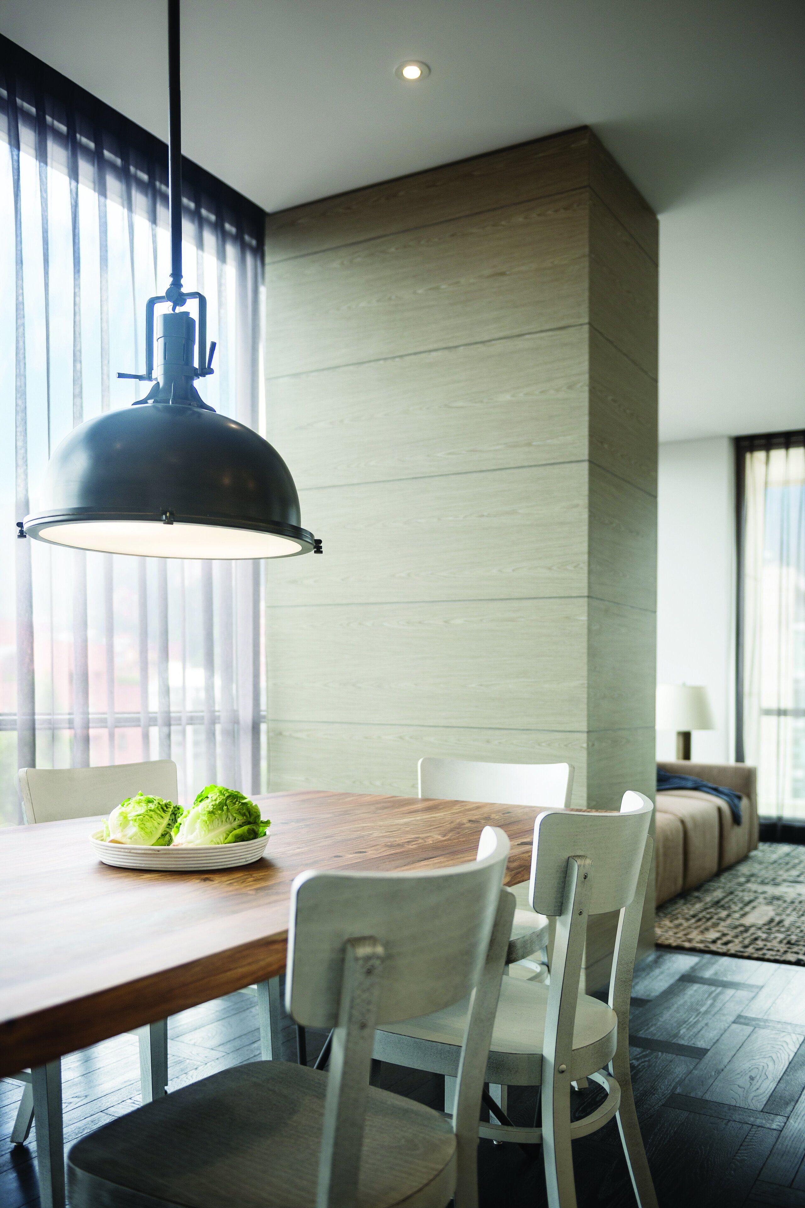 A modern dining area with a wooden table, two chairs, and a hanging pendant light.
