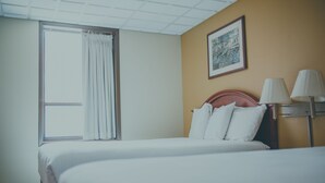 A hotel room with a bed, a window with curtains, a wall-mounted lamp, and a framed picture. - Hotel Ottumwa (Ottumwa)